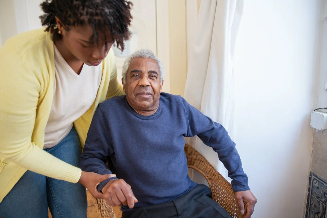 Woman helping an elderly man out of chair